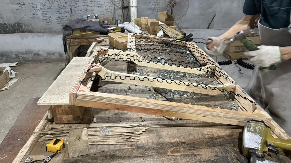 Workers fitting sinuous springs to wooden seat frames