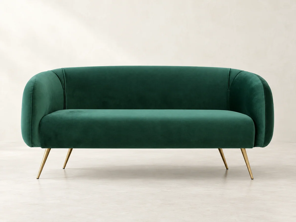 Green curved sofa with tapered metallic legs on a neutral studio background