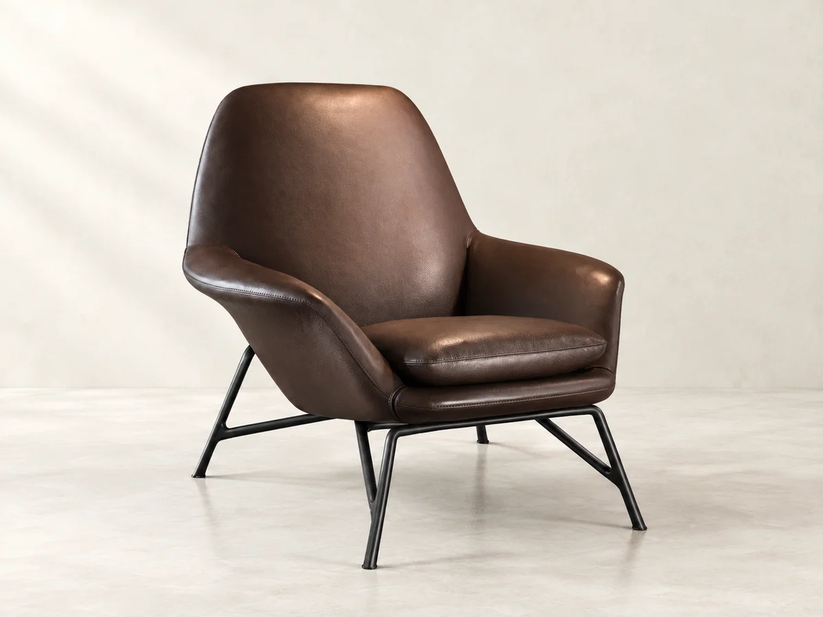 Brown sculpted upholstered lounge chair on a slender dark metal frame