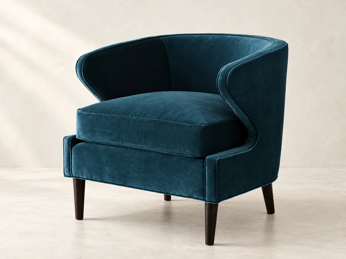 Deep teal upholstered tub chair with a curved back and slender dark legs
